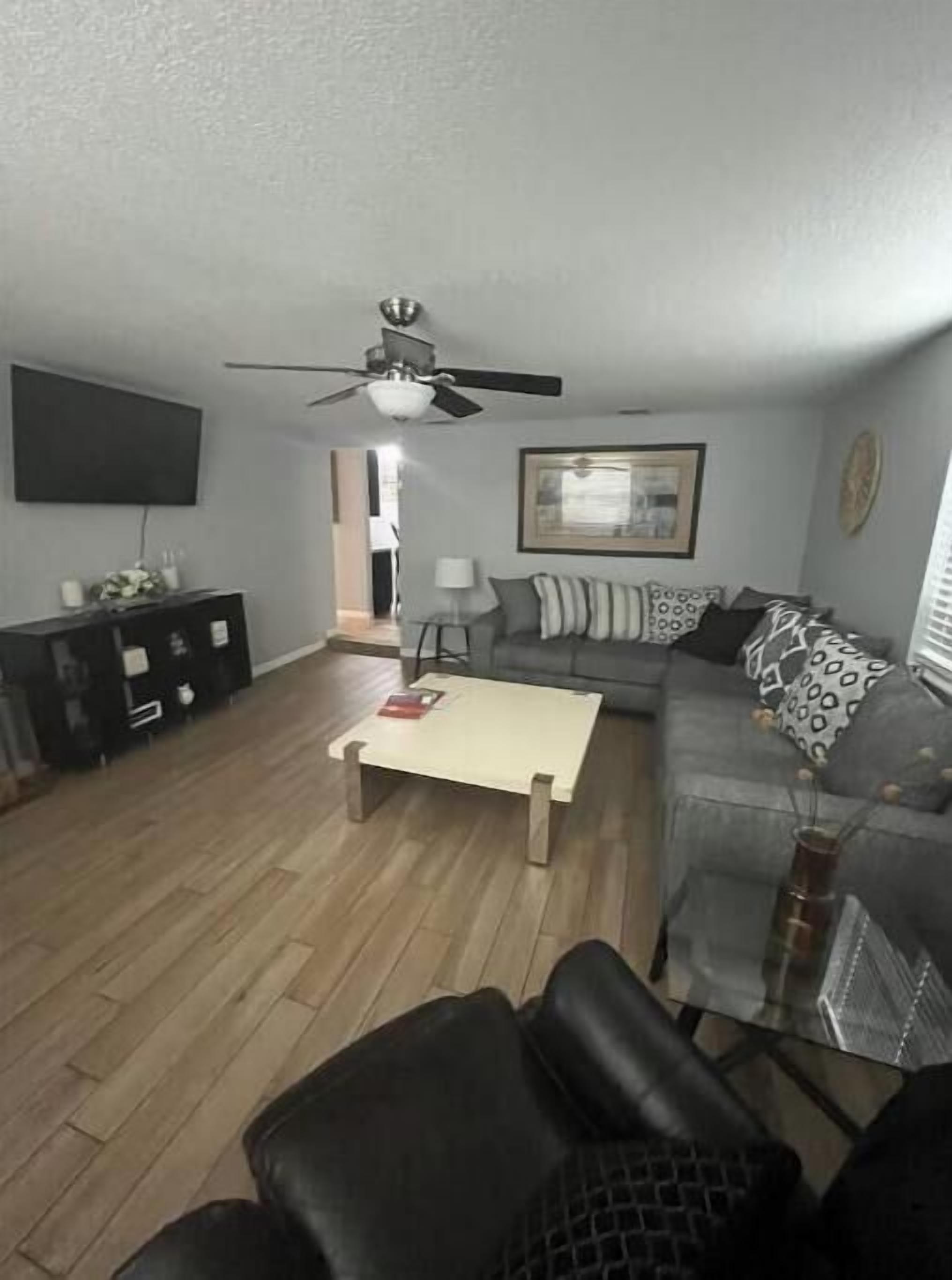 A living room with a sofa, a coffee table, a TV, and a ceiling fan.
