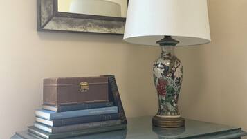 A dresser with a lamp, a mirror, and a stack of books.