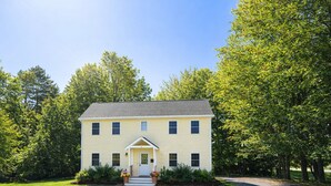 A two-story house with a front porch, surrounded by a well-maintained lawn and trees. - Lush Coastal Downtown Home - Beaches & Shopping (Freeport)