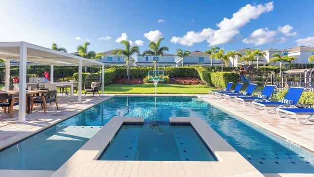 A swimming pool with lounge chairs and a covered seating area. - Modern Luxury 5BR Pool Movie-Game Rm @Encore 7770 (Kissimmee)