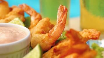 Un plato de camarones fritos con salsa para mojar y gajos de limón.
