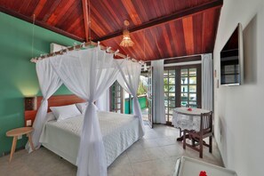 A bedroom with a four-poster bed, a small table with a chair, and a TV mounted on the wall. - Pousada Ecoporto (Ipojuca)