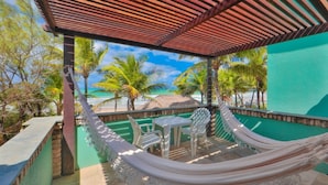 A hammock under a wooden pergola with a view of the beach and palm trees. - Pousada Ecoporto (Ipojuca)