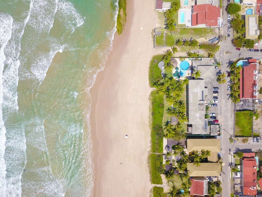 Vista aérea de una zona costera con playa, piscina y edificios residenciales.