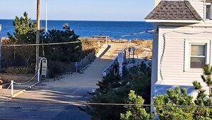 Una calle residencial con una casa, un portón y vista al océano.