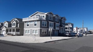 Un edificio residencial de varios pisos con un balcón, entrada para vehículos y coches estacionados.