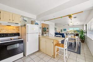 A modern kitchen with a stove, refrigerator, and dining area.