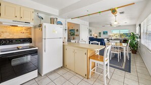 A modern kitchen with a stove, refrigerator, and dining area.