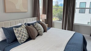 A neatly made bed with a quilted duvet, multiple pillows, and a bedside lamp. - Brand New! Huge 3-bedroom, 2,500 sqft  3rd and 4th floor condo, private rooftop. (Raleigh)