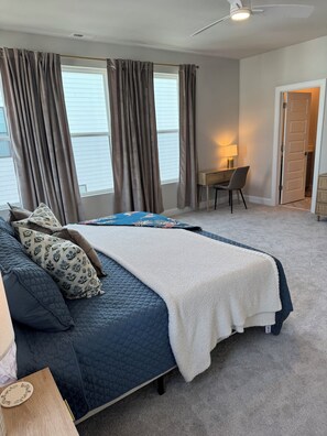 A bedroom with a bed, a desk, and a chair.