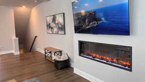 A modern living room with a flat-screen TV, a fireplace, and abstract art on the wall. - Brand New! Huge 3-bedroom, 2,500 sqft  3rd and 4th floor condo, private rooftop. (Raleigh)