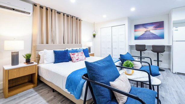 Une chambre d’hôtel moderne équipée d’un lit, d’une table de chevet, d’une lampe et d’un coin repas avec des chaises et une table.