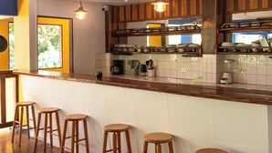 Una cocina moderna con taburetes de madera, encimera blanca y lámparas colgantes.
