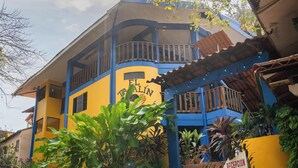 Un edificio de dos pisos con fachada azul y amarilla, un balcón y un letrero que dice "EL TALIN".