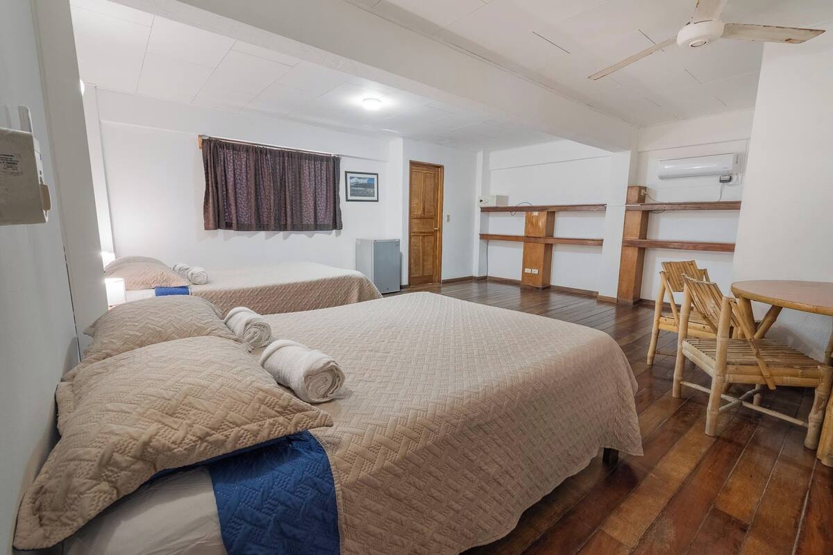 A hotel room with two beds, a desk, chairs, and a wardrobe.
