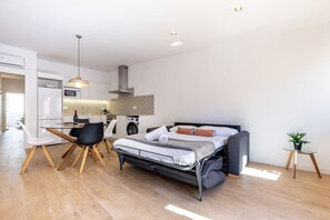 A compact room with a bed, a dining table with chairs, a kitchenette, and a small potted plant. - Merceria 3 by Unik Tarragona (Tarragona)