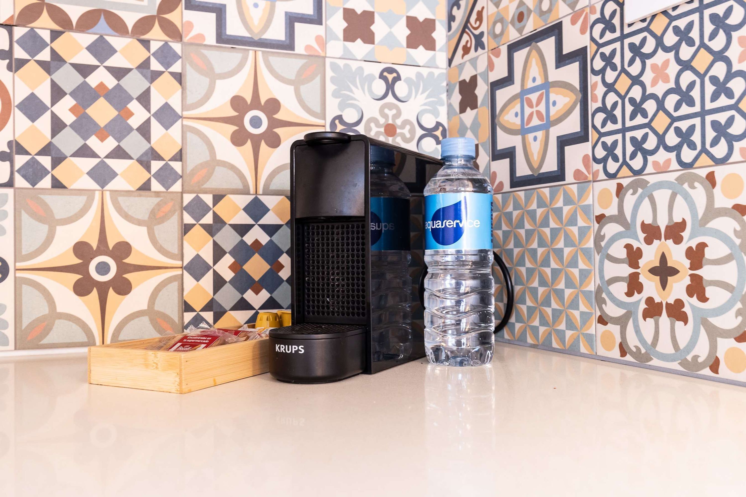 Un área de cocina con cafetera, una botella de agua y una caja de snacks.