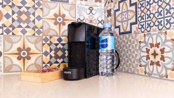 Un área de cocina con cafetera, una botella de agua y una caja de snacks.