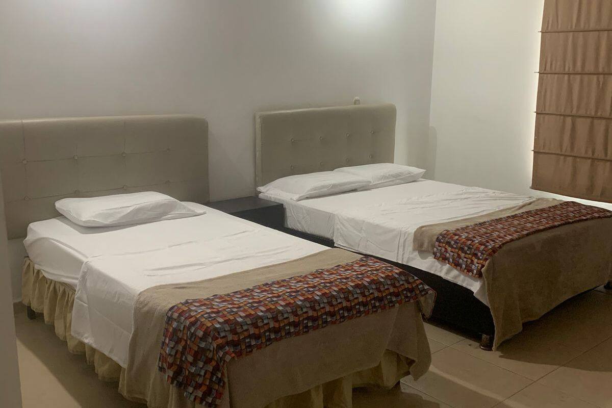 A hotel room with two beds, each with a headboard, and a patterned blanket on one bed.