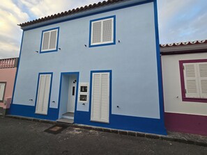 Ein zweistöckiges Gebäude mit weißen Fensterläden und einer blauen Fassade.