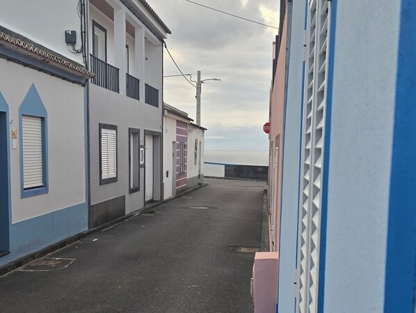 Eine schmale Straße mit Gebäuden an beiden Seiten, ein Stoppschild und ein Blick auf das Meer in der Ferne.