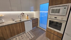 Una cocina moderna con lavavajillas, fregadero y horno empotrado.