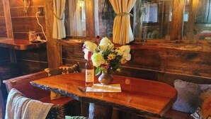 A wooden table with a vase of flowers, a bottle, and a menu. - Rustic Luxury w/Horses-Historic Whiskey Distillery (Watsontown)