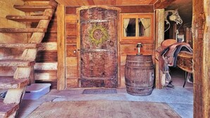 A rustic wooden interior with a wooden door, a window, a wooden barrel, and a wooden staircase. - Rustic Luxury w/Horses-Historic Whiskey Distillery (Watsontown)
