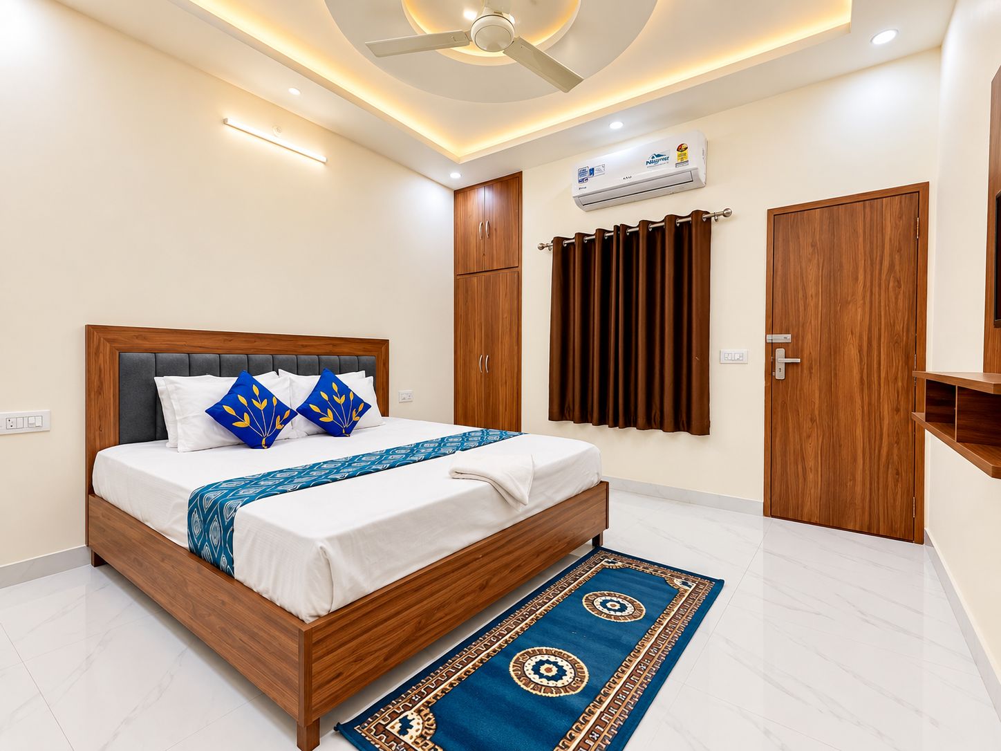 A modern bedroom with a wooden bed, a ceiling fan, an air conditioning unit, and a brown door.