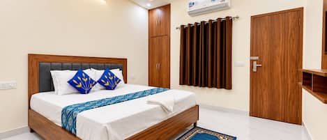 Ein modernes Schlafzimmer mit einem hölzernen Bett, einem Deckenventilator, einer Klimaanlage und einer braunen Tür.