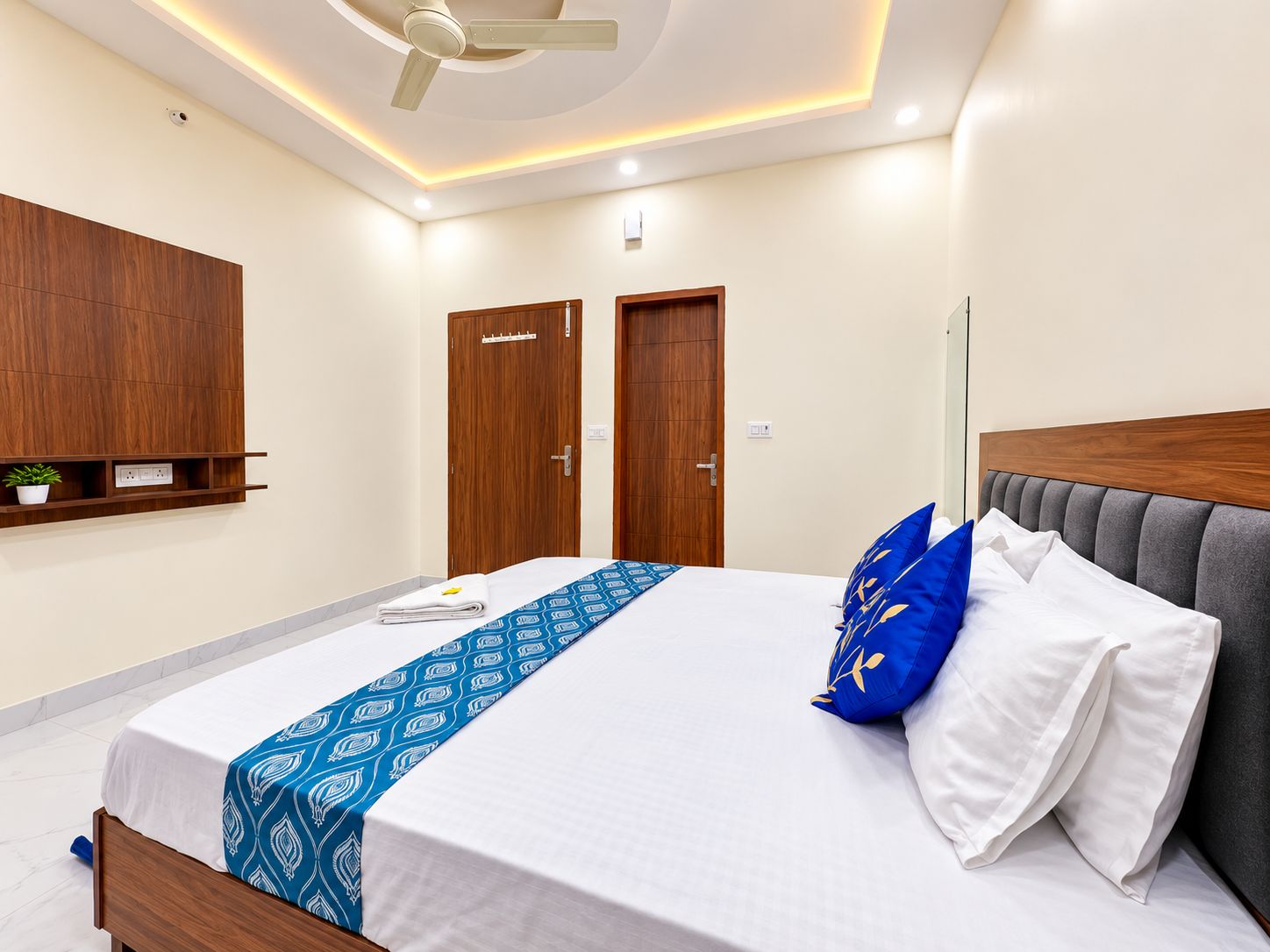 Un dormitorio moderno con una cama, un ventilador de techo y puertas de madera.