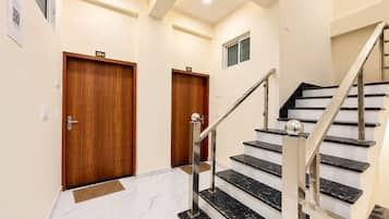 A modern interior with a marble staircase, wooden doors, and a minimalist design.