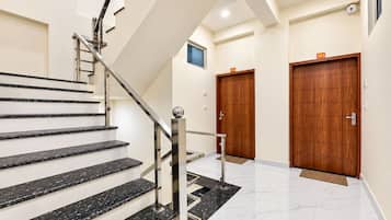 A modern staircase with black marble steps and stainless steel railings leading to a landing.