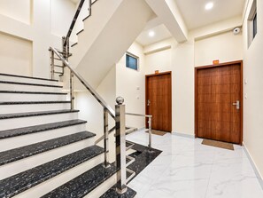 A modern staircase with black marble steps and stainless steel railings leading to a landing.