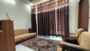 Ein Wohnzimmer mit einer Couch, einem Sessel, einer Holzkabine und einem gemusterten Teppich.