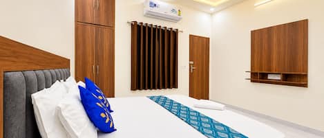 Une chambre d’hôtel équipée d’un lit, d’une armoire, d’un climatiseur et d’un ventilateur de plafond.