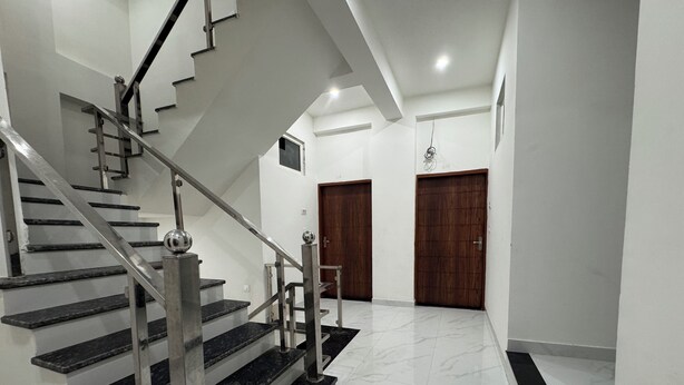 Eine moderne Treppe mit Metallgeländern und schwarzen Stufen, die zu einer Zwischenebene führt.