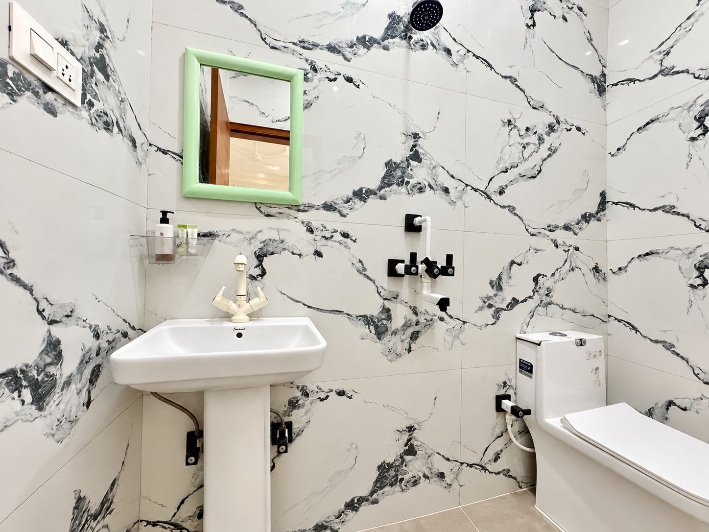 A bathroom with a white sink, a mirror, a shower, and a toilet.