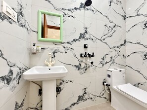 Un baño con lavamanos blanco, espejo, ducha e inodoro.