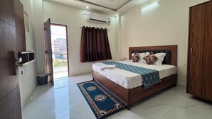 Ein Schlafzimmer mit Bett, Holzschrank, Deckenventilator, Klimaanlage, Badezimmertür und Blick ins Freie.