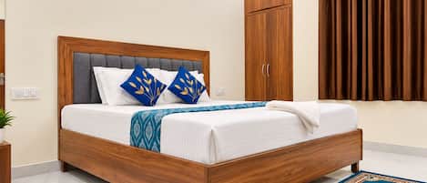 Un dormitorio moderno con cabecera tapizada gris, estructura de cama de madera y manta estampada.
