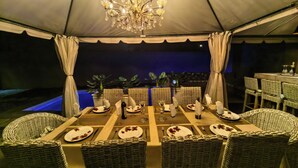 An outdoor dining area with a tent canopy, wicker chairs, and a chandelier. - Bryanston Palms Accommodation  (Sandton)