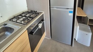 Une cuisine de taille réduite équipée d’une cuisinière à gaz, d’un four à micro-ondes encastré, d’un réfrigérateur et d’un évier.