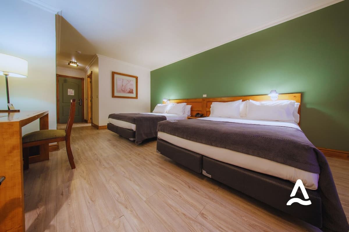 A hotel room with two beds, a desk, and a chair.