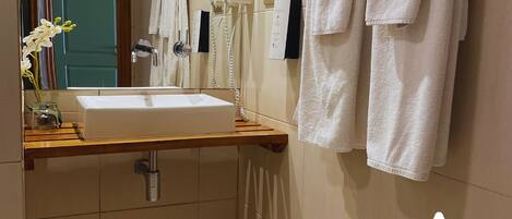 Un baño con lavamanos, espejo, toallero y secador de pelo.