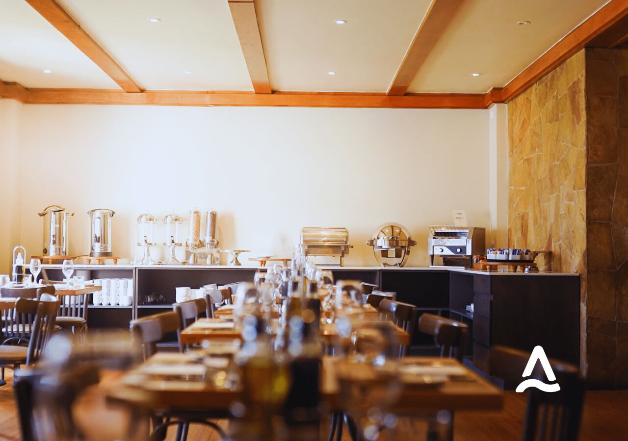 Een restaurant met houten balken in het plafond, een stenen muur en een bar met diverse apparaten.