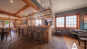 Un grand espace bar doté d’un îlot central, de tabourets et d’étagères remplies de bouteilles et de verres.