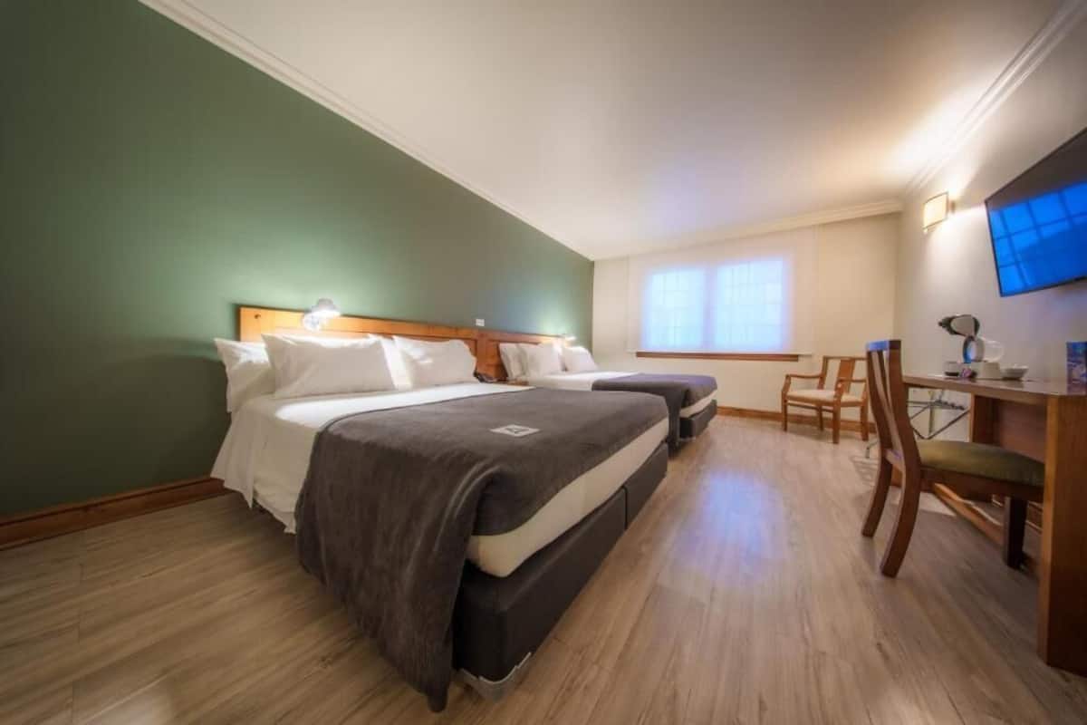 A room with two beds, a desk, and a chair.