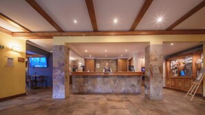 Un hall d’accueil d’hôtel avec un comptoir en pierre, un bureau d’accueil et une enseigne indiquant « ALMASUR HOTEL PUNTA ARENAS ».