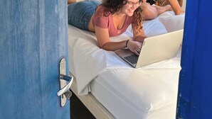 Une pièce avec un lit, une porte et une personne qui lit un livre.